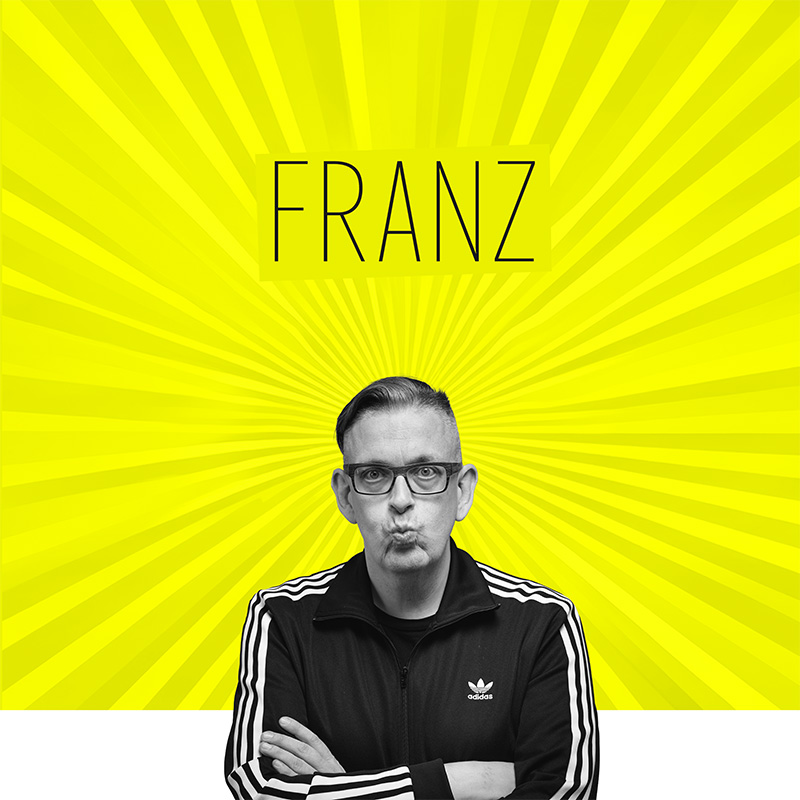 Franz Moped mit verschränkten Armen und spitzem Kussmund vor gelbem Hintergrund mit radialem Lichtmotiv, darüber der Schriftzug „Franz“ als grafischer Einstieg zur Seite Biografie