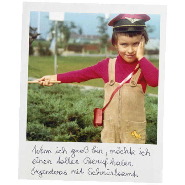 Kindheitsfoto von Franz Moped in Latzhose aus Schnürlsamt mit rotem Pullover und Schaffnerkappe, darunter handschriftliche Aufschrift „Wenn ich groß bin, möchte ich einen tollen Beruf haben. Irgendwas mit Schnürlsamt“